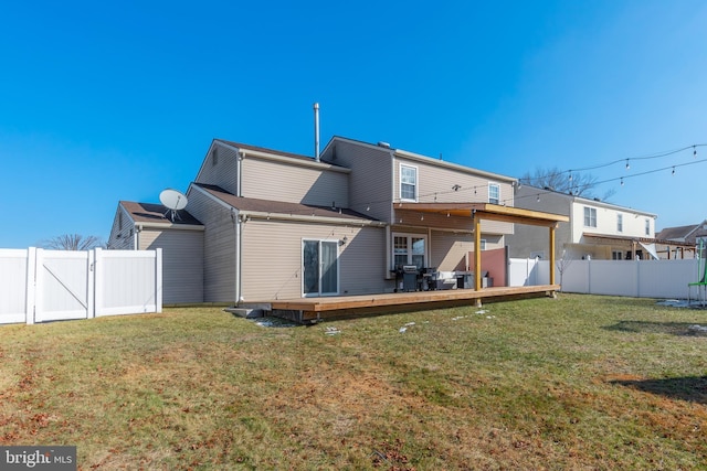 rear view of house featuring a wooden deck and a lawn