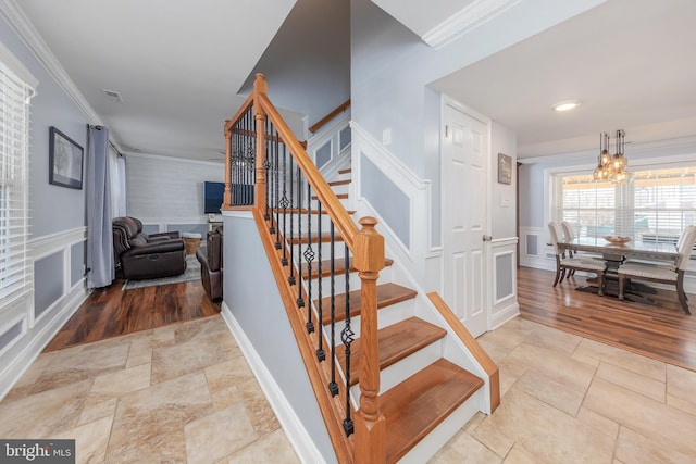 stairs featuring a chandelier and crown molding