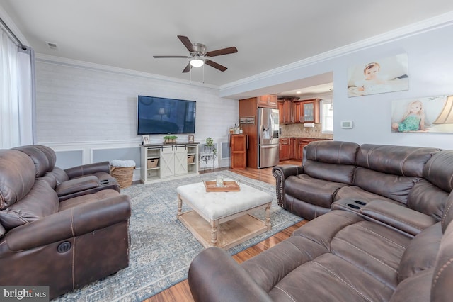 living room with light wood-type flooring, ceiling fan, and crown molding