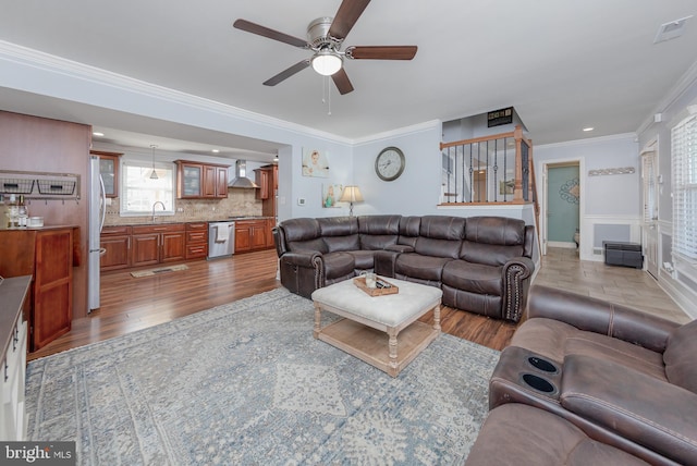 living room with ceiling fan, sink, ornamental molding, and light hardwood / wood-style flooring