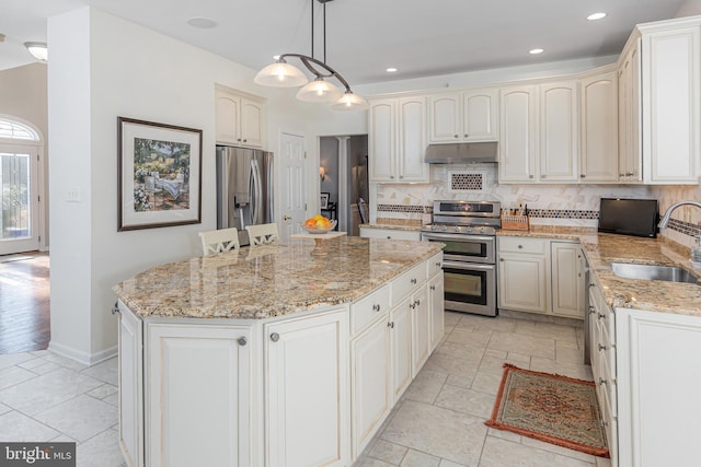 kitchen with hanging light fixtures, a center island, decorative backsplash, appliances with stainless steel finishes, and sink