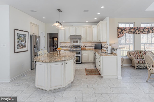 kitchen with stainless steel appliances, decorative light fixtures, tasteful backsplash, kitchen peninsula, and light stone countertops