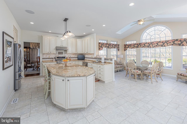 kitchen featuring ceiling fan, stainless steel appliances, decorative light fixtures, and plenty of natural light