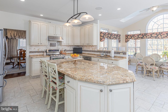 kitchen with a center island, decorative light fixtures, tasteful backsplash, appliances with stainless steel finishes, and sink