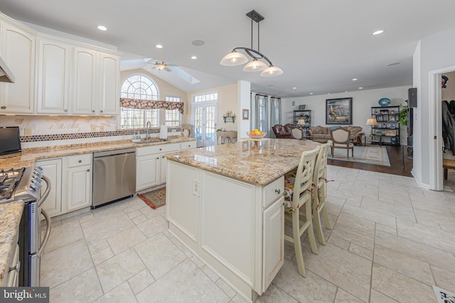 kitchen with decorative light fixtures, stainless steel appliances, a kitchen island, ceiling fan, and sink