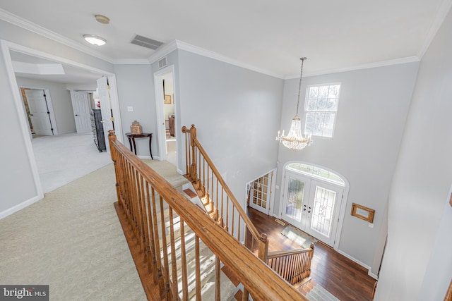 hallway with crown molding, french doors, carpet, and a chandelier