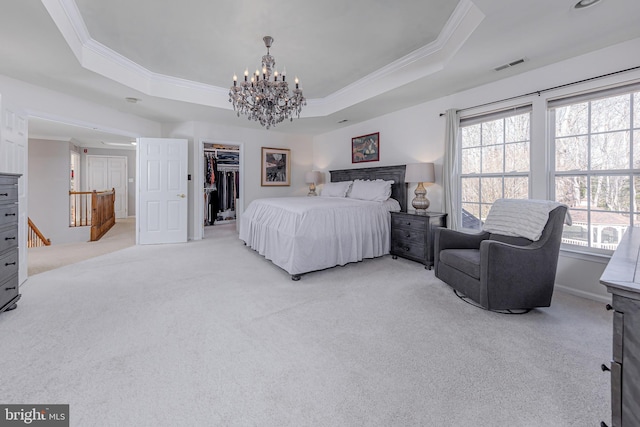 bedroom with a chandelier, light colored carpet, crown molding, a spacious closet, and a tray ceiling