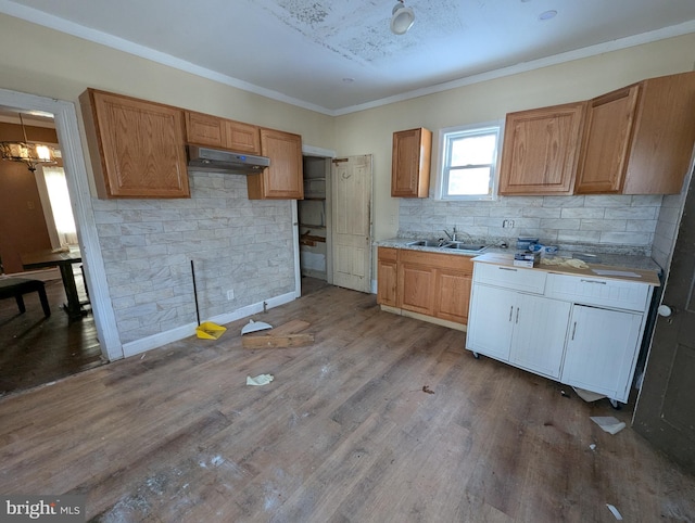 kitchen with sink, tasteful backsplash, a notable chandelier, hardwood / wood-style floors, and ornamental molding