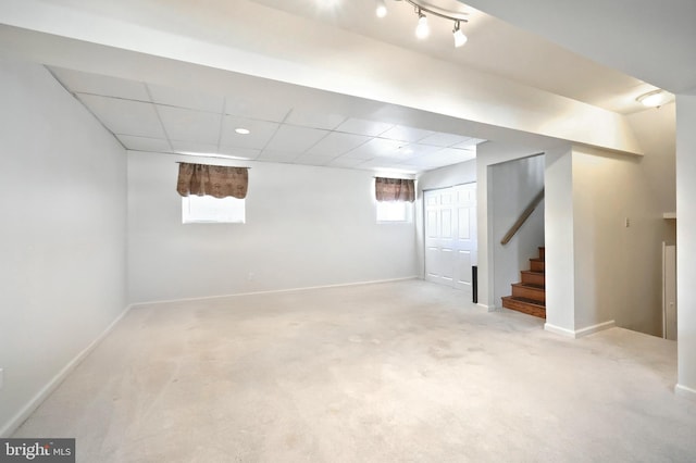 basement with a paneled ceiling and light carpet