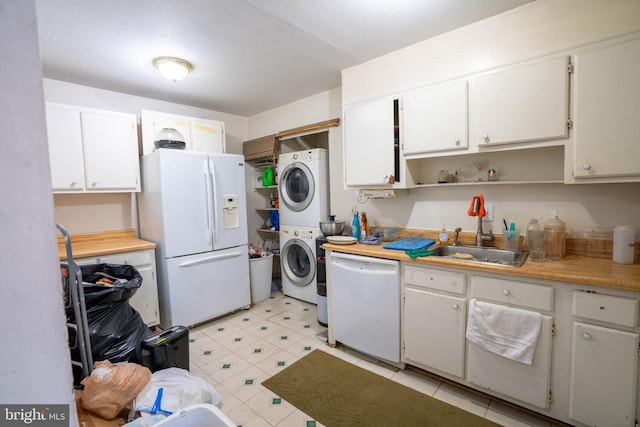 kitchen featuring stacked washing maching and dryer, sink, white cabinets, and white appliances