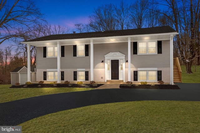 raised ranch featuring a storage unit and a yard