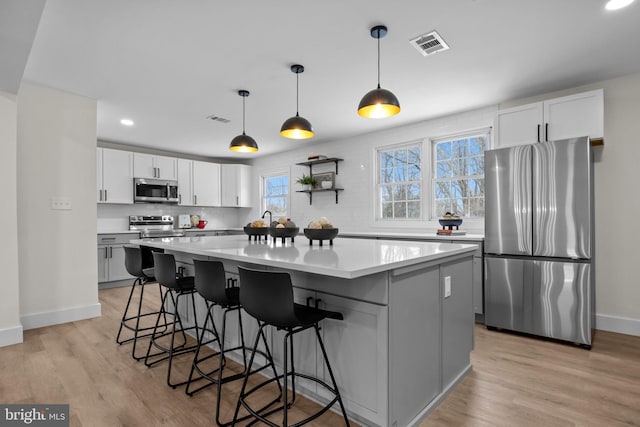 kitchen with stainless steel appliances, white cabinetry, and a kitchen island