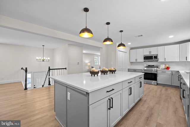 kitchen featuring appliances with stainless steel finishes, a center island, pendant lighting, and gray cabinetry