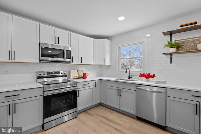 kitchen featuring stainless steel appliances, light hardwood / wood-style floors, gray cabinetry, and sink