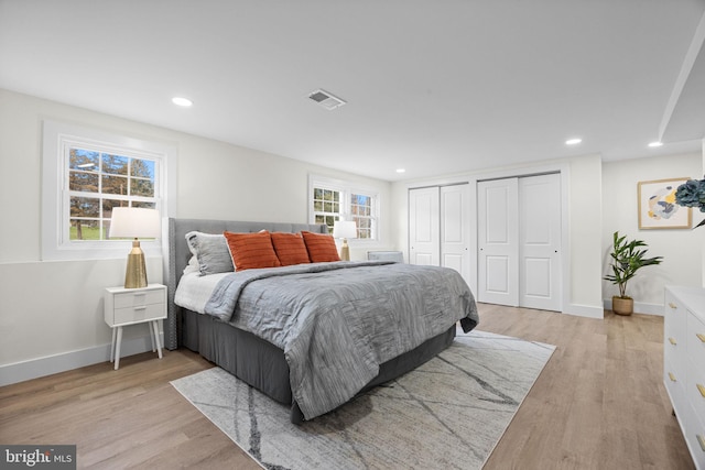 bedroom with two closets and light hardwood / wood-style flooring