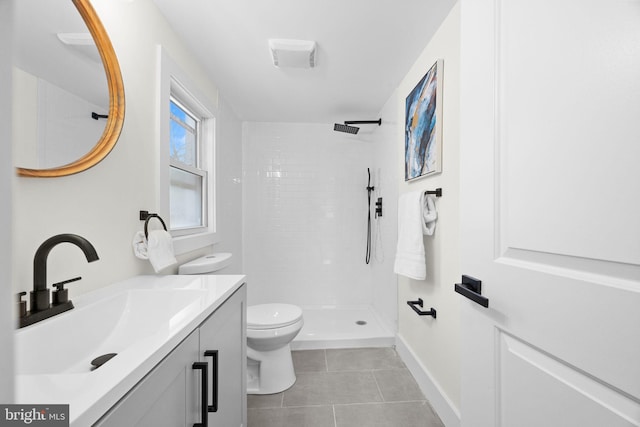 bathroom featuring tile patterned flooring, vanity, toilet, and a tile shower