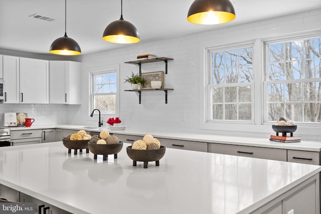 kitchen with decorative light fixtures, sink, a wealth of natural light, and tasteful backsplash