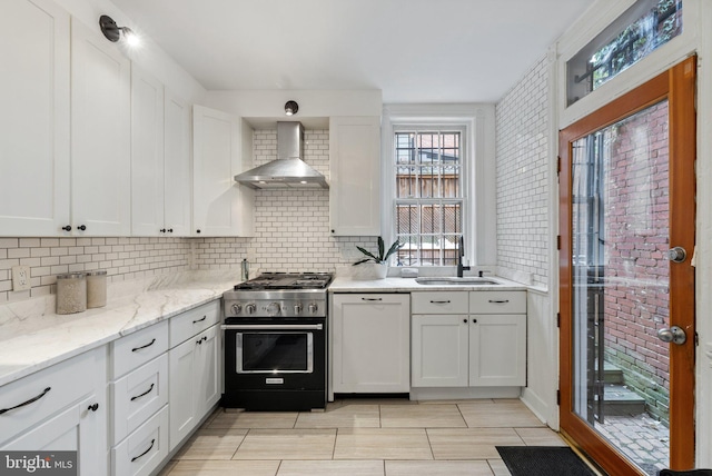 kitchen with sink, white cabinets, stainless steel range, and wall chimney range hood