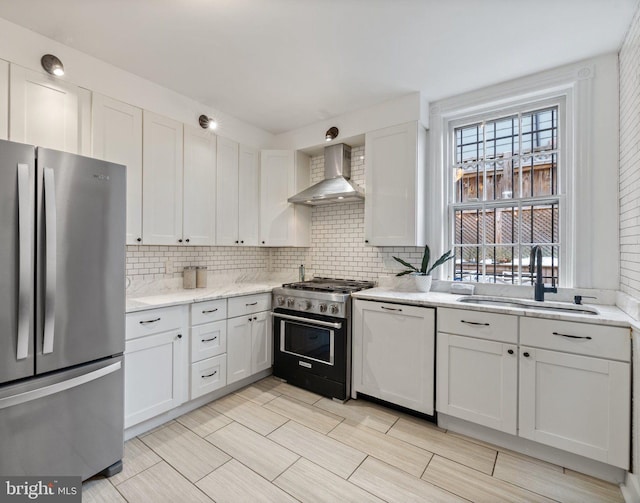 kitchen featuring sink, white cabinetry, wall chimney range hood, and stainless steel appliances