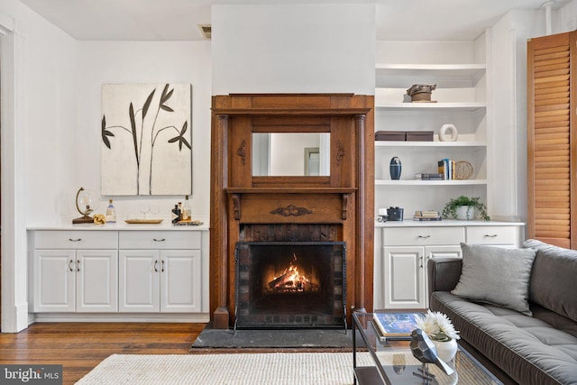 living room featuring built in shelves and dark wood-type flooring