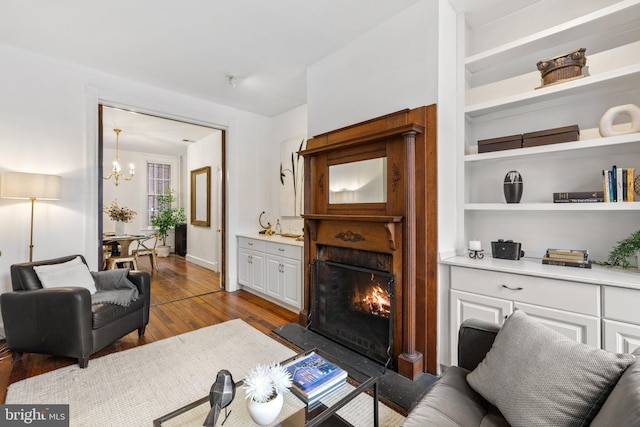 living room featuring built in features, a chandelier, and light hardwood / wood-style flooring