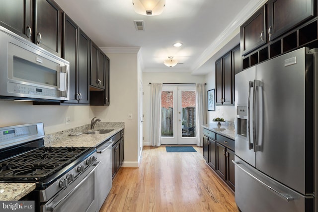 kitchen with light stone counters, stainless steel appliances, sink, and dark brown cabinets