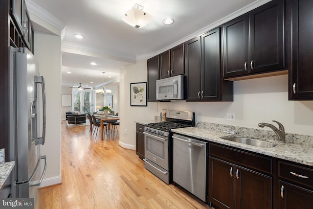 kitchen featuring sink, light stone counters, light hardwood / wood-style floors, stainless steel appliances, and crown molding