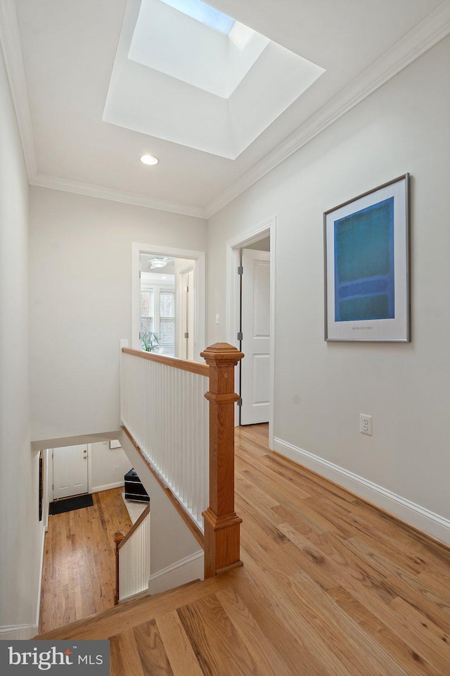 stairs with hardwood / wood-style flooring, ornamental molding, and a skylight