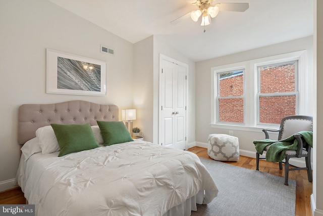 bedroom featuring vaulted ceiling, hardwood / wood-style floors, ceiling fan, and a closet