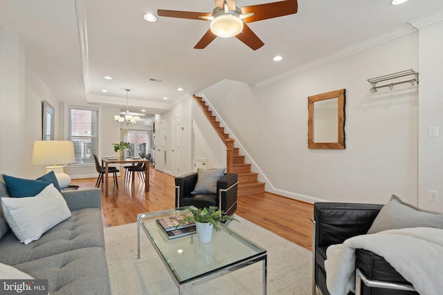 living room featuring crown molding, ceiling fan with notable chandelier, and light hardwood / wood-style floors