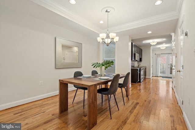 dining area featuring crown molding, a chandelier, light hardwood / wood-style floors, and french doors