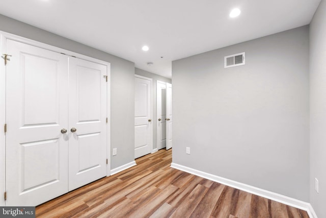 unfurnished bedroom with light wood-type flooring and a closet