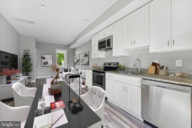 kitchen with sink, white cabinets, stainless steel appliances, and light hardwood / wood-style floors