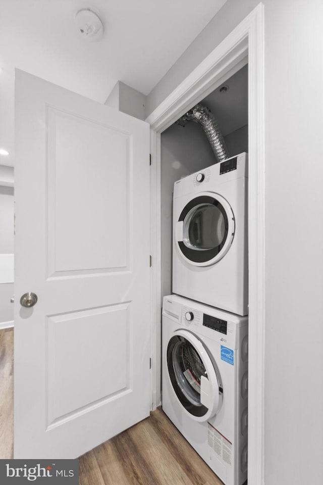 washroom with stacked washer and dryer and hardwood / wood-style flooring