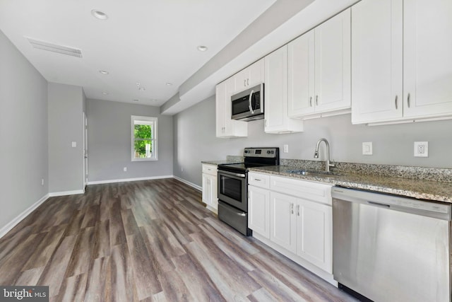 kitchen with white cabinets, sink, light wood-type flooring, light stone counters, and stainless steel appliances