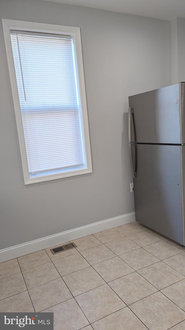 interior space with light tile patterned floors and stainless steel refrigerator