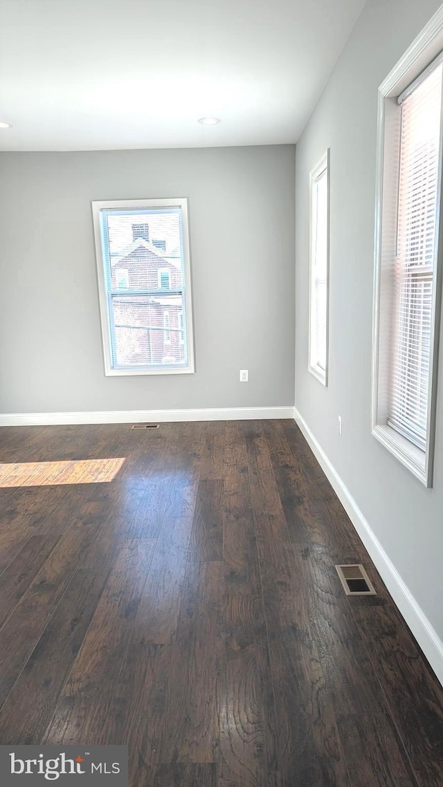 unfurnished room with dark wood-type flooring