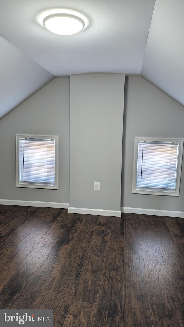 additional living space with vaulted ceiling and dark hardwood / wood-style flooring