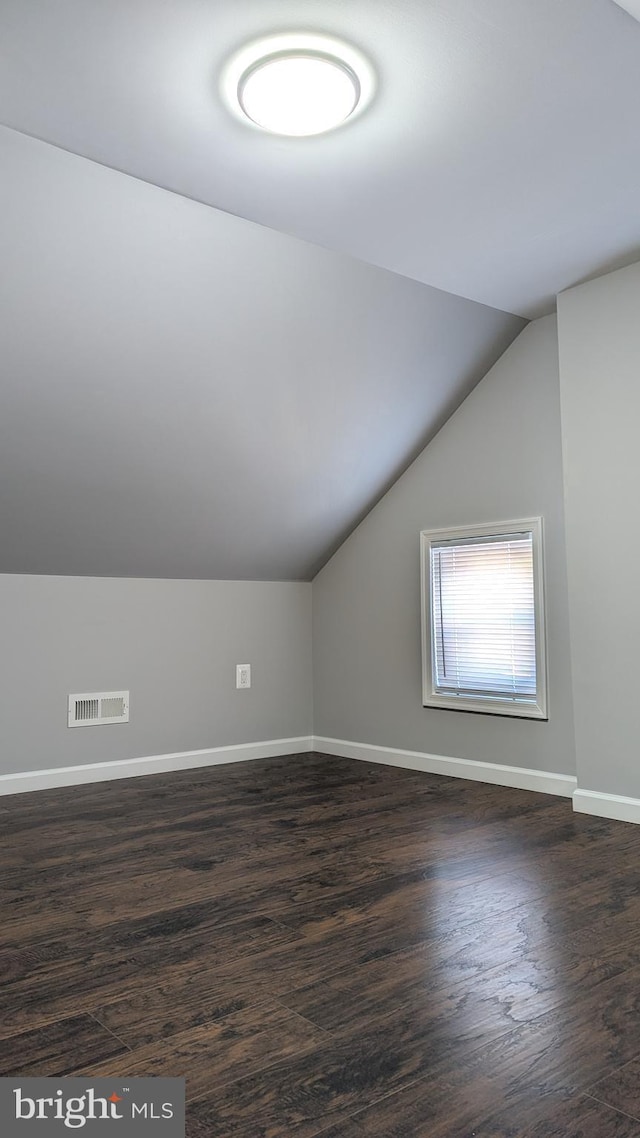 bonus room with dark hardwood / wood-style floors and vaulted ceiling