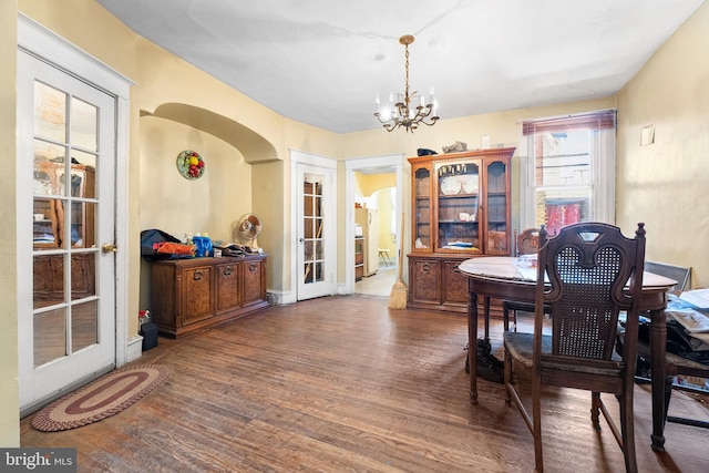 dining space with french doors, dark wood-type flooring, and a chandelier