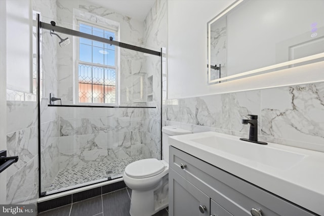 bathroom with toilet, vanity, tile walls, and a healthy amount of sunlight