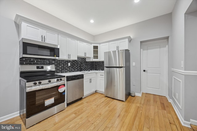 kitchen featuring sink, white cabinetry, light wood-type flooring, tasteful backsplash, and appliances with stainless steel finishes