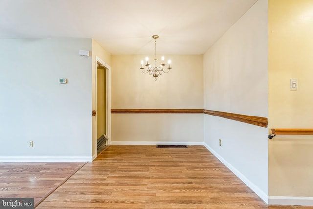 unfurnished room featuring hardwood / wood-style floors and an inviting chandelier