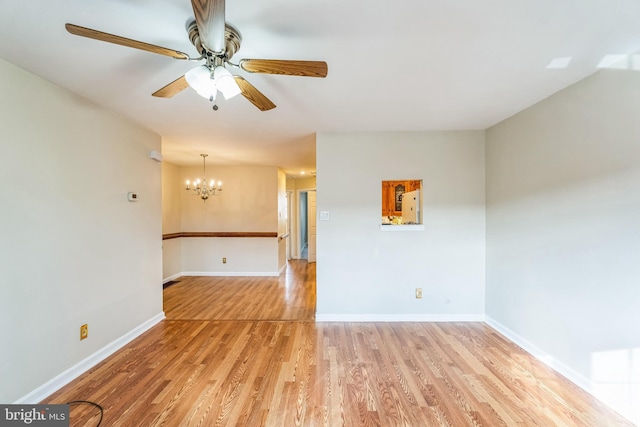 unfurnished room with ceiling fan with notable chandelier and light wood-type flooring