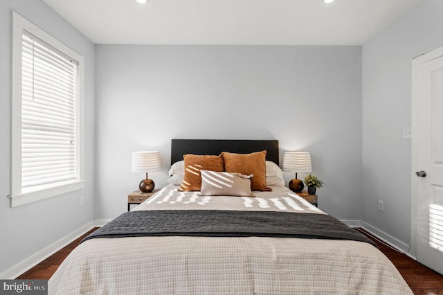 bedroom with multiple windows and dark hardwood / wood-style flooring