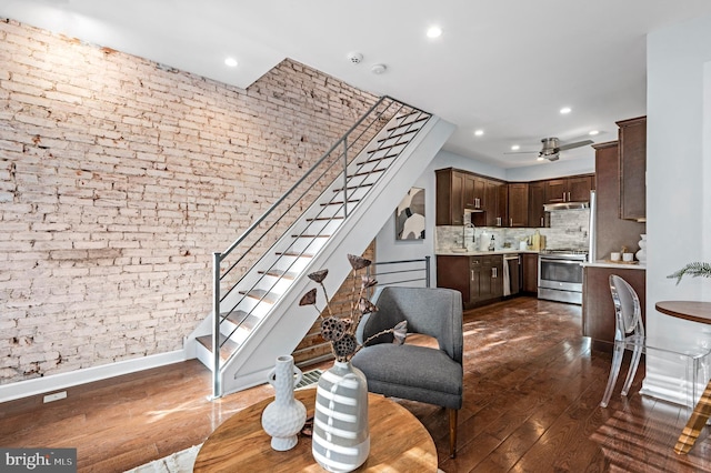 living room featuring ceiling fan, brick wall, and dark hardwood / wood-style floors