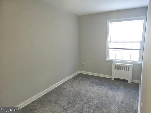 carpeted spare room featuring a healthy amount of sunlight and radiator heating unit