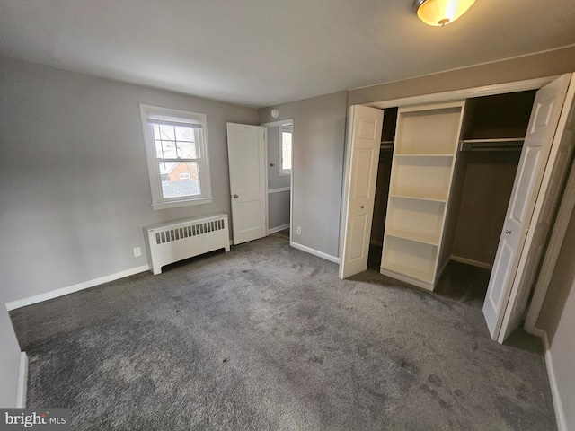 unfurnished bedroom featuring radiator heating unit, a closet, and dark colored carpet