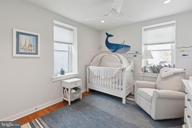 bedroom with ceiling fan, dark hardwood / wood-style flooring, and a crib