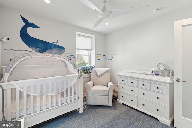 carpeted bedroom featuring ceiling fan and a crib